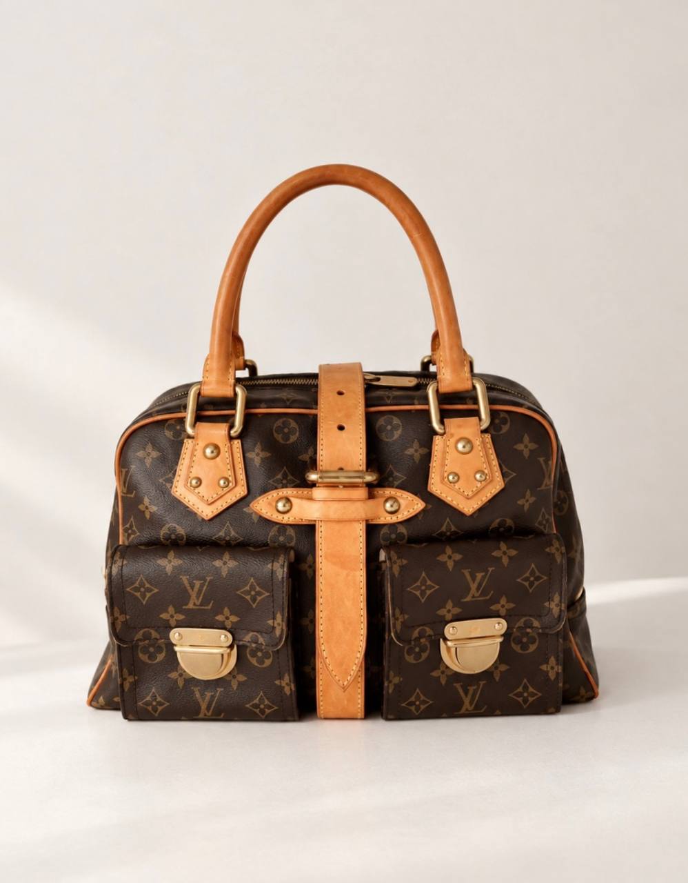 Cтильная и вместительная сумка Louis Vuitton Manhattan в фирменном канвасе Monogram с отделкой из натуральной кожи Vachetta и золотистой фурнитурой